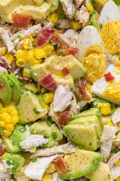 a salad with hard boiled eggs, corn and avocado is shown in close up