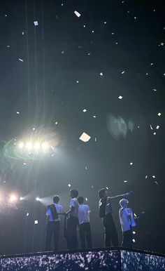 some people are standing on a stage with confetti falling from the sky in front of them