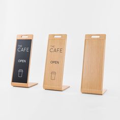 three wooden signs that say the cafe, open and the cafe is on each side