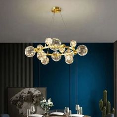 a modern chandelier hanging over a dining room table with blue walls and chairs