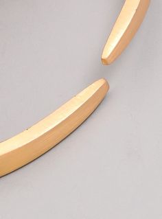 a pair of gold - plated scissors on a gray surface, with one blade missing