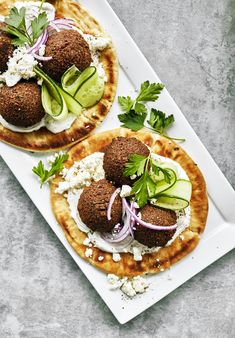 two pita breads with cucumber, onions and feta cheese on them