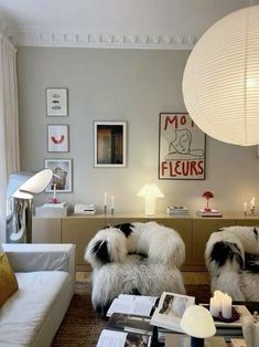 a living room filled with white furniture and lots of pictures on the wall above it