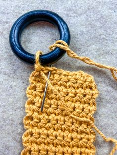 a crochet bag with a blue hook on the end and a black ring hanging from it