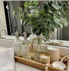 a wooden tray with candles, soaps and flowers in front of a bathroom mirror