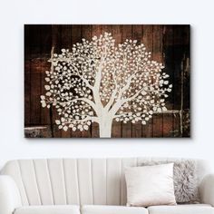 a living room with a white couch and a painting on the wall above it that has a tree