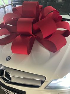 a white car with a large red bow on the hood