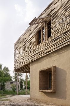 a building made out of sticks and bricks with an open window on the outside wall