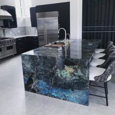 a large kitchen with marble counter tops and stainless steel appliances, along with black cabinets