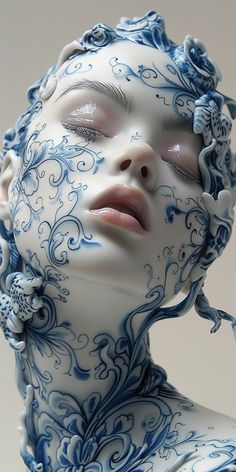 a woman's face is covered in blue and white porcelain art work, with her eyes closed to the side