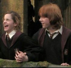 two harry potters are laughing and holding their hands together