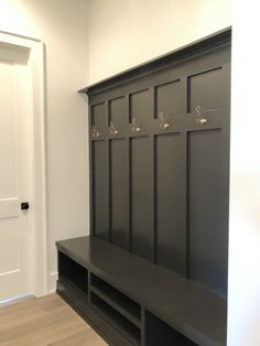 an empty entryway with a bench and coat rack on the wall next to it