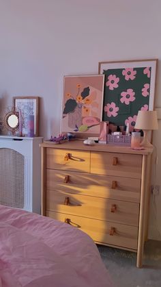 a bedroom with a dresser, bed and pictures on the wall above it's headboard