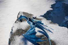 a blue dragon statue sitting on top of snow covered ground