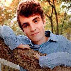 a young man leaning on a tree branch