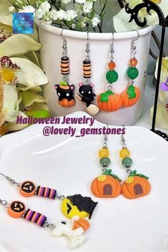 halloween jewelry is displayed in front of a white vase with flowers and pumpkins on it