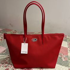 2 Large Handles One Zippered Interior Net Pocket Lacoste Branded Zipper Embroidered Crocodile Branding Size: Approx. 48 X 30 X 14.5 Cm Red Tote Shoulder Bag For Shopping, Polo Ralph Lauren Faffia Bag, Designer Red Tote Bag, Lacoste Bag Aesthetic, Red Tote Shoulder Bag With Luggage Sleeve, Lacoste Pink Bag, Lacoste Tote Bag, Lacoste Bag, Tan Tote Bag