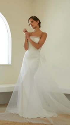 a woman in a white wedding dress is posing for the camera with her hands on her hips