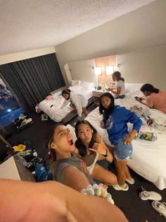 a group of young people sitting on top of a bed in a bedroom next to each other