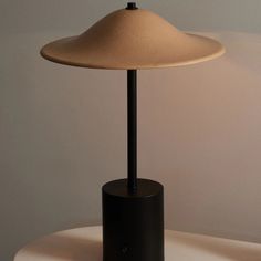 a table lamp sitting on top of a white table next to a black vase with a flower in it