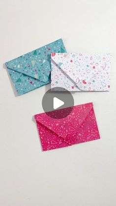 three envelopes with different designs on them, one is pink and the other is blue