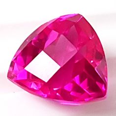 a pink diamond on a white surface with no other image to describe, it is very bright and shiny