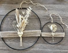 two pieces of art made out of wood and wire with dried flowers in the center