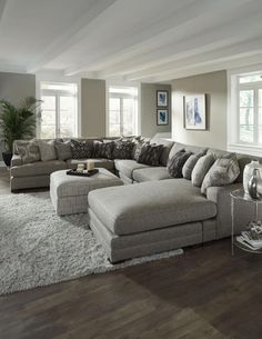 a large sectional couch sitting on top of a rug in a living room next to a window