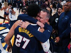 two basketball players hugging each other in front of an arena full of people and fans