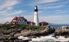 a light house sitting on top of a rocky cliff next to the ocean with waves crashing in front of it