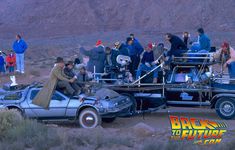 the back to the future car is parked in the desert with people standing around it