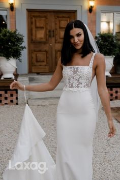 a woman in a wedding dress holding a white bag