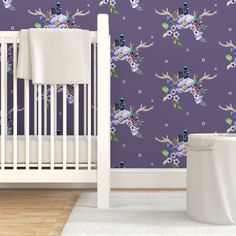 a white crib in front of a purple wallpaper with blue and pink flowers