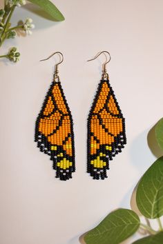 a pair of beaded earrings with an orange butterfly on the front and black wings on the back