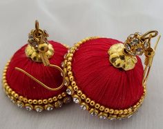 two red and gold earrings sitting next to each other on top of a white surface