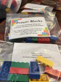 some legos are sitting in plastic bags on the table and one has a sign that says prayer blocks