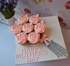 a cupcake with pink frosting and flowers on it sitting next to a vase