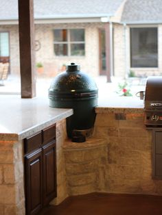 an outdoor bbq and grill in the middle of a patio area with stone walls