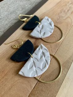 two white and black earrings sitting on top of a wooden table