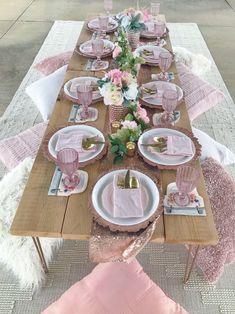 the table is set with pink and white plates, napkins, and place settings