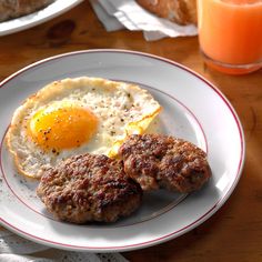 two breakfast foods on a white plate with red trimmings and an orange juice in the background