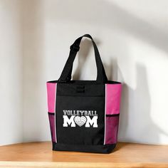 Calling all loud and proud Volleyball moms! Whether you're cheering from the courtside or heading to the park, this Volleyball mom bag is the perfect accessory to show off your team spirit. It's sized to carry all your snacks, water, sunscreen, and anything else you might need during the game. Order yours today and be the envy of the Volleyball court. ⋙ TOTE BAG DETAILS ⋘ * Measurements: 14.5" h x 13" w x 5" d * Zippered main compartment * Front pocket with pen loop * 2 side mesh pockets for water bottle * Full color Volleyball Mom design printed on front ⋙ HOW TO ORDER ⋘ Select your tote bag color from the drop down Soccer Mom design is printed on the front of all totes 🛒ADD TO CART ❤️ Is this a gift? Be sure to write a gift message so they know who sent them this special gift! 🚚 FREE E Black Sports Bags With Letter Print, Black Sports Bag With Letter Print, Black Bags For Sports With School Spirit Style, Sporty Letter Print Bags For Sports, Sporty Letter Print Sports Bag, Team Mom Gifts, Volleyball Court, Mom Bag, Tote Bag With Pockets