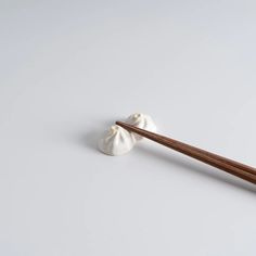 chopsticks with two small white dumplings on them sitting next to each other