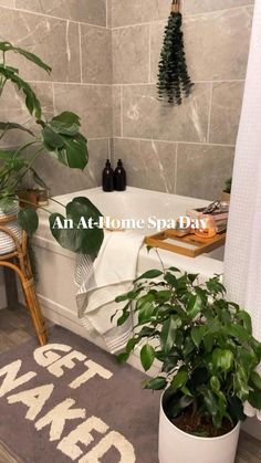 a bathroom with plants in the tub and towels on the floor