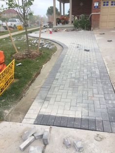 a brick walkway is being laid in front of a house