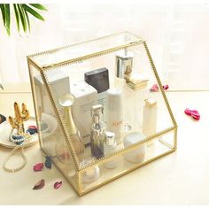 a clear box filled with personal care items on top of a white table next to a potted plant