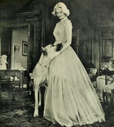 an old photo of a woman in a long dress with a dog on her lap