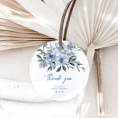 a white paper fan with blue flowers on it and the words thank you written on it