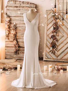 a white wedding dress on display in front of a wooden wall with candles and lights