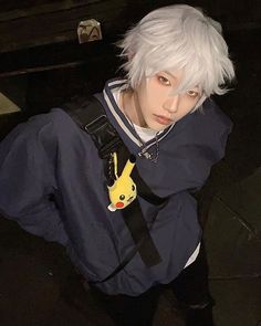 a man with white hair wearing a blue shirt and carrying a pokemon pikachu backpack